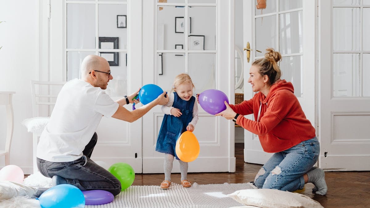 A joyful family playing with colorful balloons indoors, capturing a fun bonding moment.